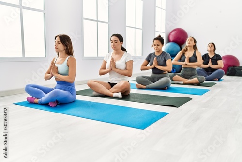 Group of young hispanic women concentrated training yoga at sport center.