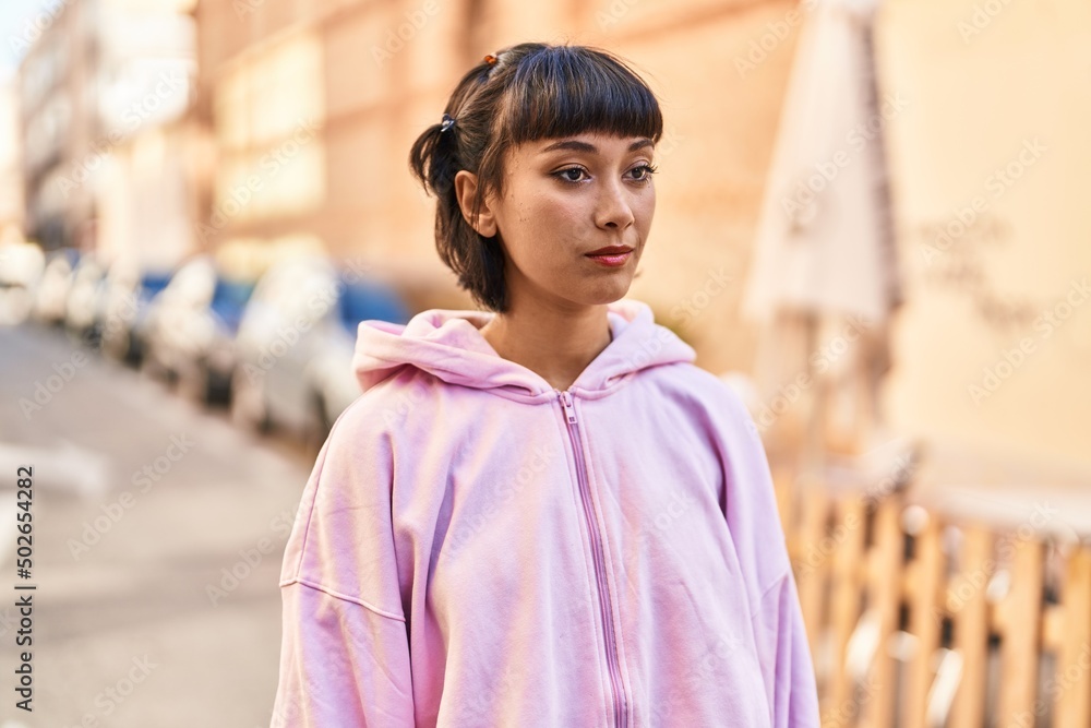 Fototapeta premium Young woman standing with relaxed expression at street