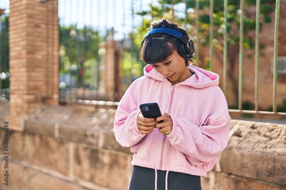Fototapeta premium Young woman listening to music at street