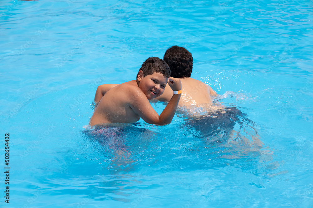 happy boy doing figure with arm strength in the pool on vacation happy boy doing figure with arm strength in the pool on vacation