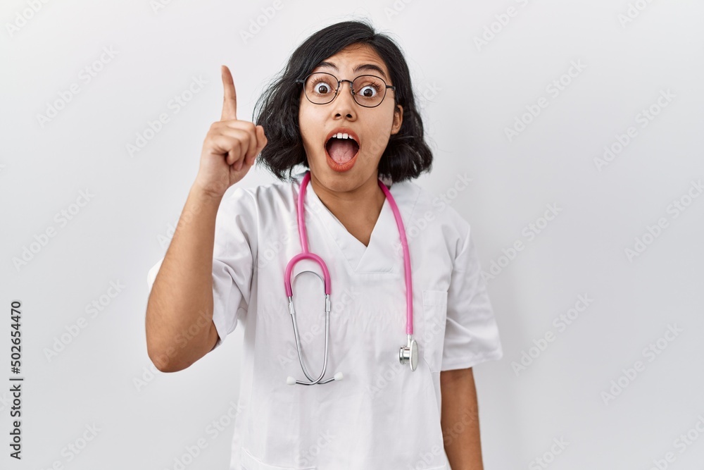 Young hispanic doctor woman wearing stethoscope over isolated background pointing finger up with successful idea. exited and happy. number one. Young hispanic doctor woman wearing stethoscope over isolated background pointing finger up with successful idea. exited and happy. number one.