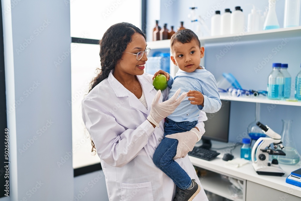 Obraz premium Mother and son wearing scientist uniform hugging each other at laboratory