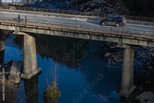 top view of the road bridge over the mountain river Prut in early spring in Yaremche Carpathians Ukraine weather sunny water pure blue trees without leaves