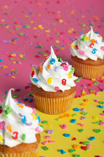 Delicious cupcakes with festive decorations presented against a contrasting pink and yellow surface.
