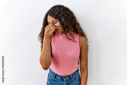 Beautiful hispanic woman standing over isolated background tired rubbing nose and eyes feeling fatigue and headache. stress and frustration concept.