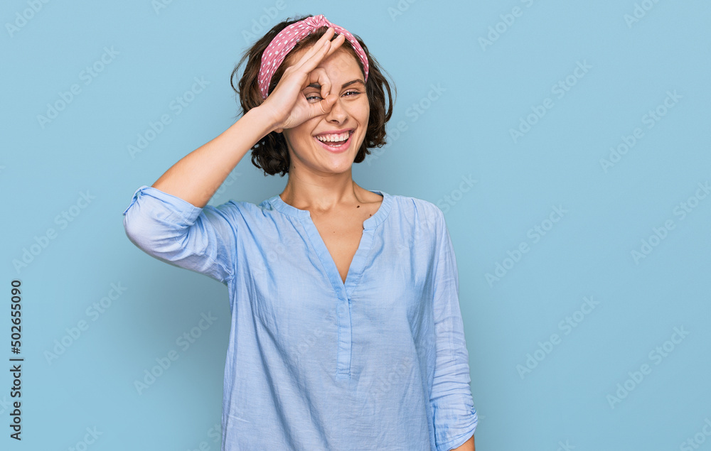 Young hispanic woman wearing casual clothes smiling happy doing ok sign with hand on eye looking through fingers Young hispanic woman wearing casual clothes smiling happy doing ok sign with hand on eye looking through fingers