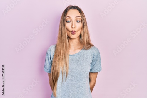 Young blonde girl wearing casual t shirt making fish face with lips, crazy and comical gesture. funny expression.