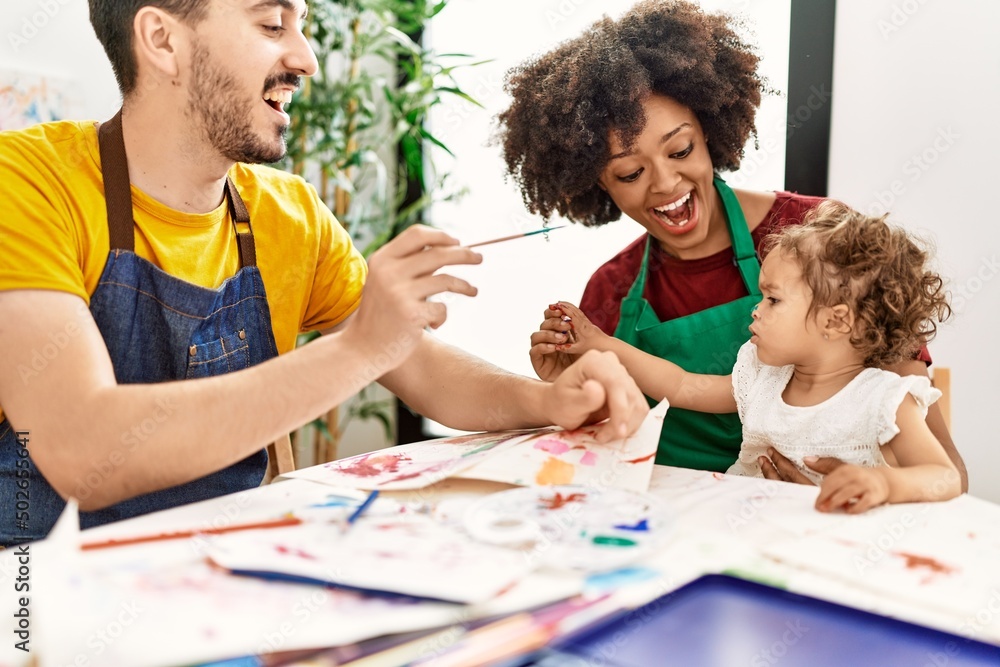 Naklejka premium Couple and daughter smiling confident painting child nose at art studio