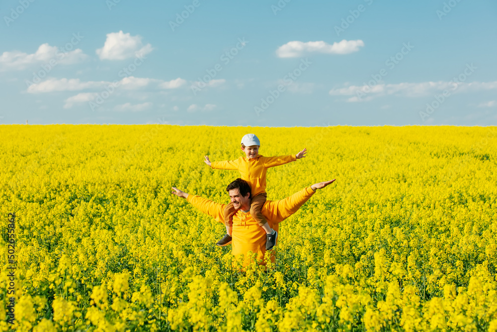 Father with a son in rapeseed field in spring time
