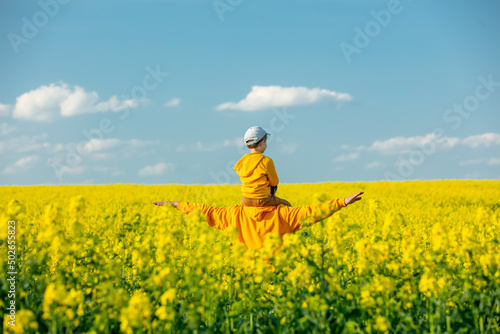 Father with a son in rapeseed field in spring time