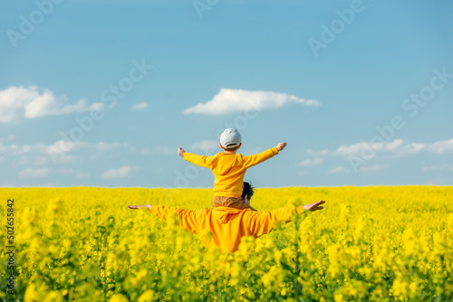 Father with a son in rapeseed field in spring time photo