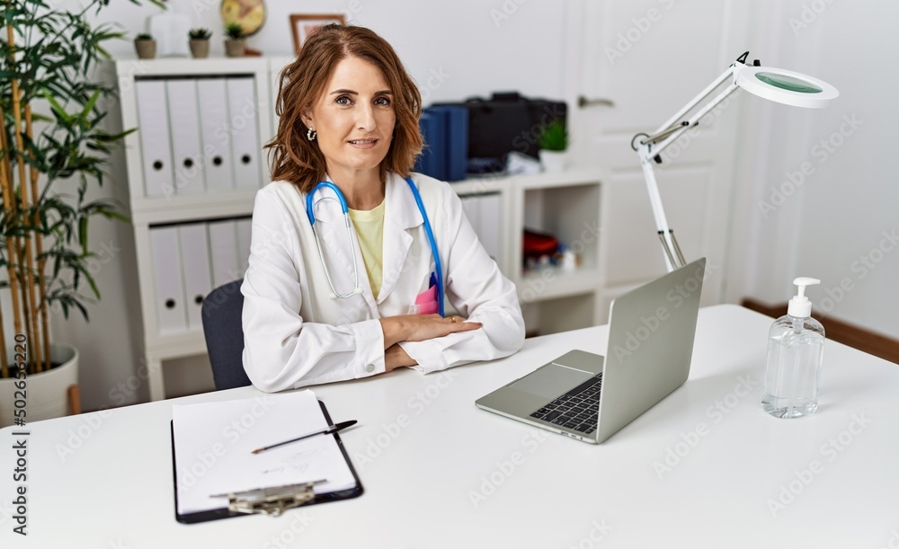Middle age hispanic woman wearing doctor uniform with arms crossed gesture at clinic Middle age hispanic woman wearing doctor uniform with arms crossed gesture at clinic