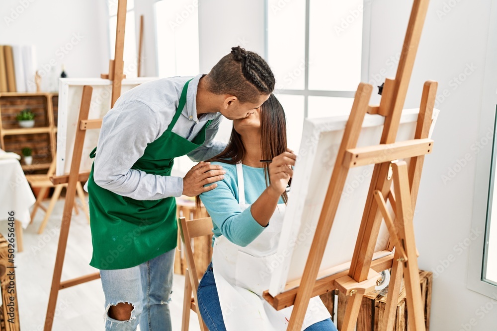 Young latin painter couple kissing and painting at art studio Young latin painter couple kissing and painting at art studio