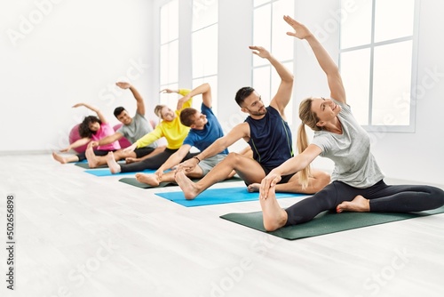 Group of young people concentrated training yoga at sport center.