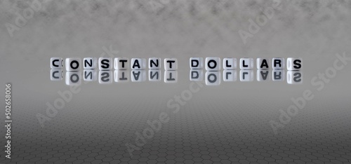 constant dollars word or concept represented by black and white letter cubes on a grey horizon background stretching to infinity