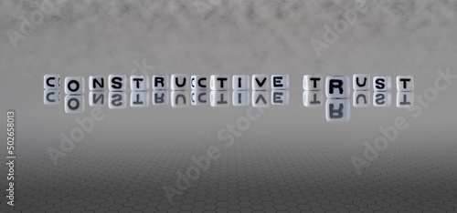 constructive trust word or concept represented by black and white letter cubes on a grey horizon background stretching to infinity