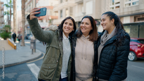 Mother and daugthers making selfie by the smartphone standing together at street © Krakenimages.com