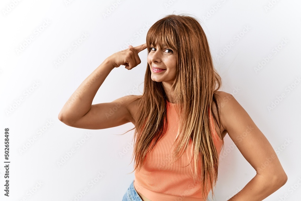 Fototapeta premium Hispanic woman with bang hairstyle standing over isolated background smiling pointing to head with one finger, great idea or thought, good memory