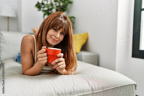Young hispanic woman smiling confident drinking coffee at home