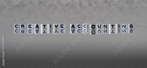 creative accounting word or concept represented by black and white letter cubes on a grey horizon background stretching to infinity