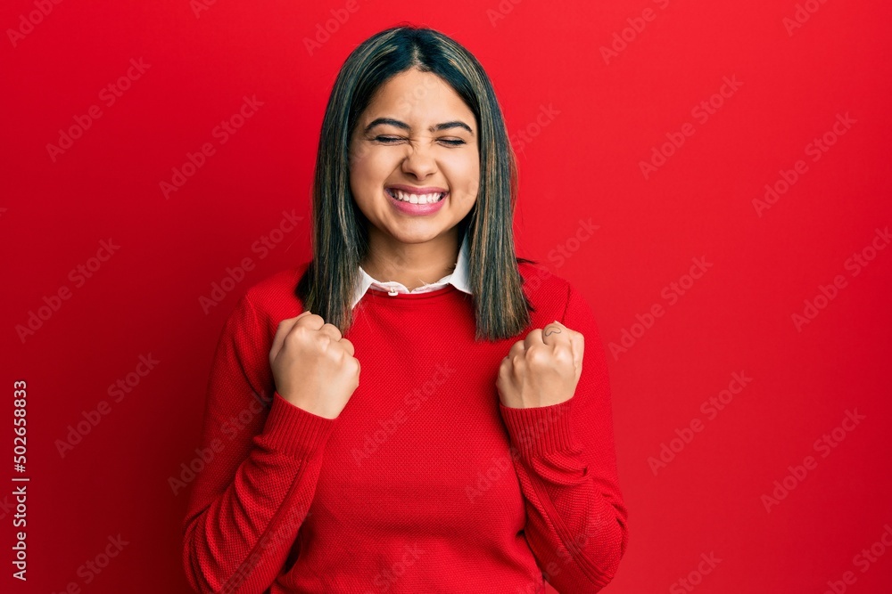 Young latin woman wearing casual clothes excited for success with arms raised and eyes closed celebrating victory smiling. winner concept. Young latin woman wearing casual clothes excited for success with arms raised and eyes closed celebrating victory smiling. winner concept.