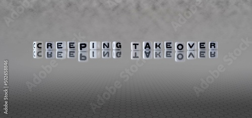 creeping takeover word or concept represented by black and white letter cubes on a grey horizon background stretching to infinity