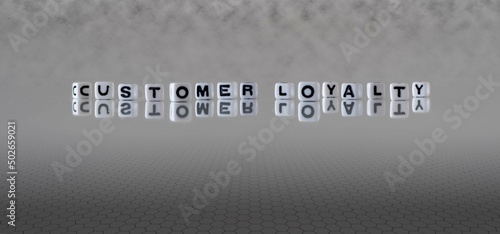 customer loyalty word or concept represented by black and white letter cubes on a grey horizon background stretching to infinity