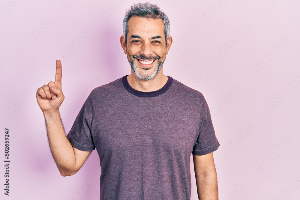 Handsome middle age man with grey hair pointing with index finger smiling with a happy and cool smile on face. showing teeth. Handsome middle age man with grey hair pointing with index finger smiling with a happy and cool smile on face. showing teeth.