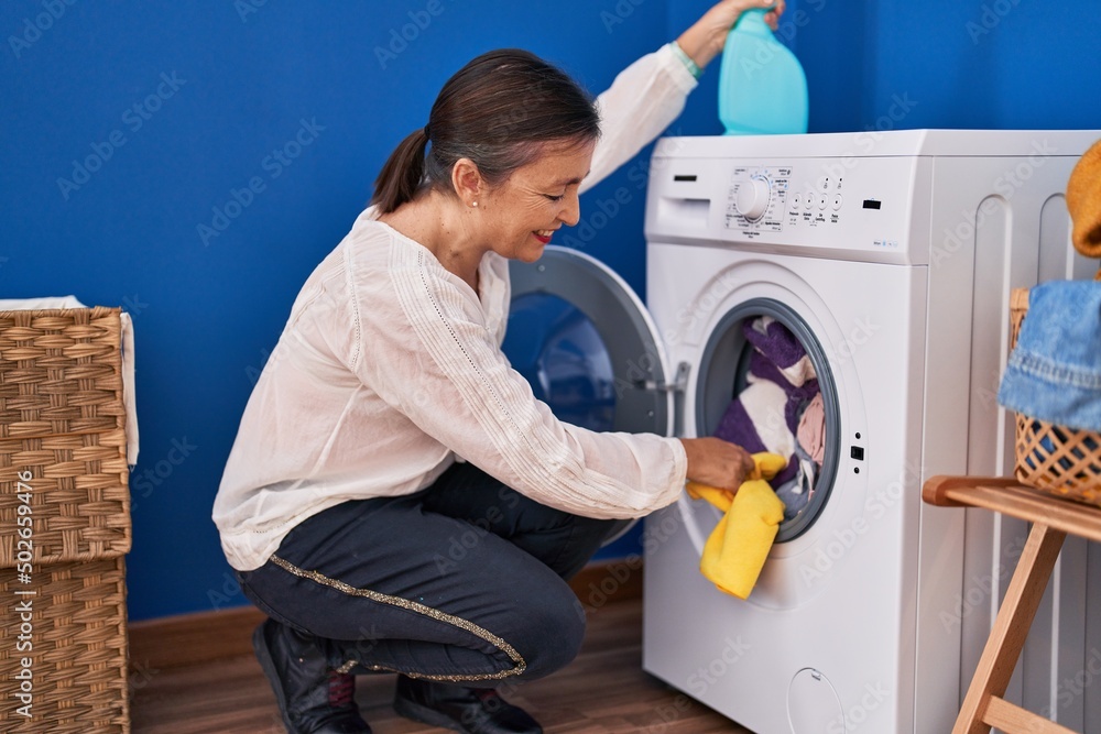 Middle age woman cleaning washing machine at laundry room Middle age woman cleaning washing machine at laundry room