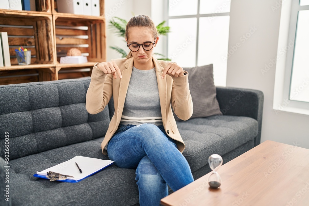 Young woman working at consultation office pointing down looking sad and upset, indicating direction with fingers, unhappy and depressed. Young woman working at consultation office pointing down looking sad and upset, indicating direction with fingers, unhappy and depressed.