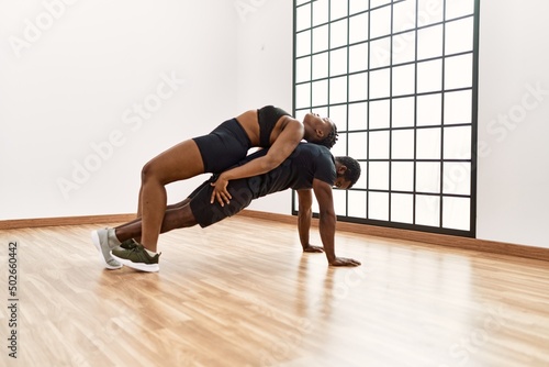Young african american sporty couple doing push-ups exercise at sport center.