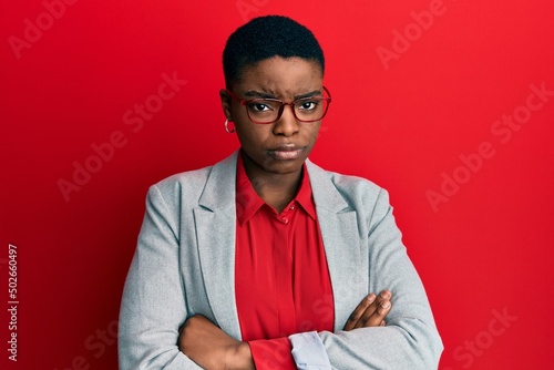 Young african american woman wearing business jacket and glasses skeptic and nervous, disapproving expression on face with crossed arms. negative person. photo