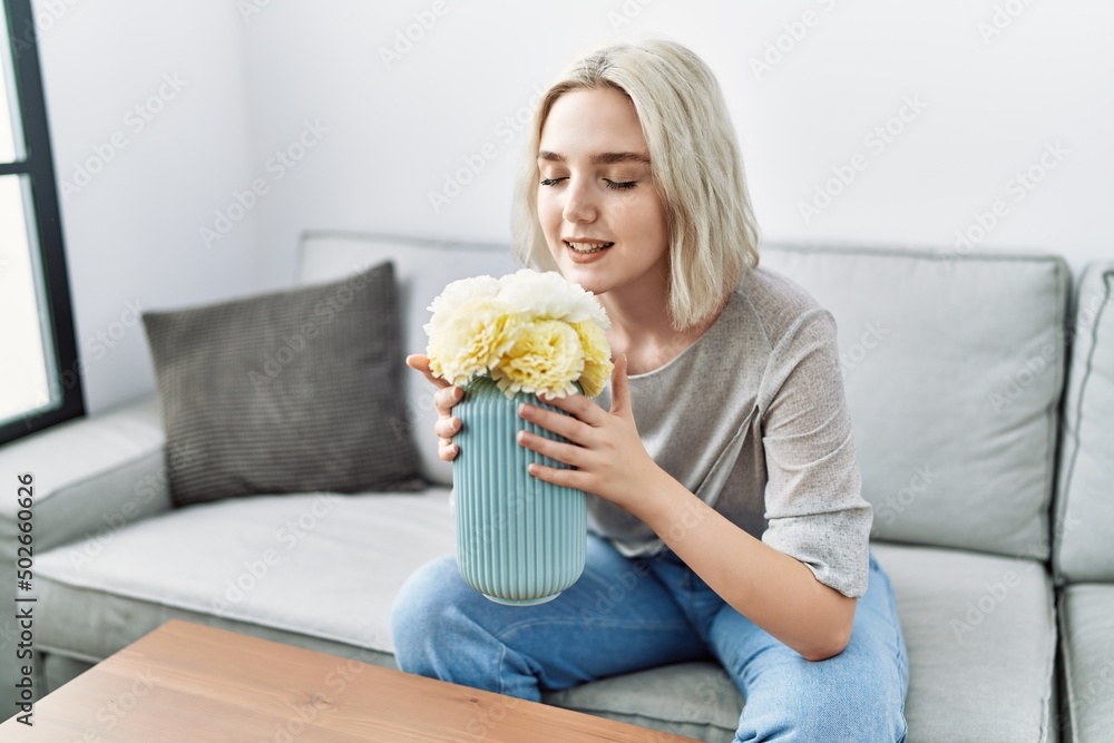 Young caucasian woman smiling confident smelling flowers at home Young caucasian woman smiling confident smelling flowers at home