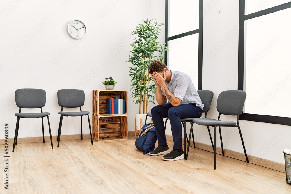 Young hispanic man desperate sitting on chair at waiting room