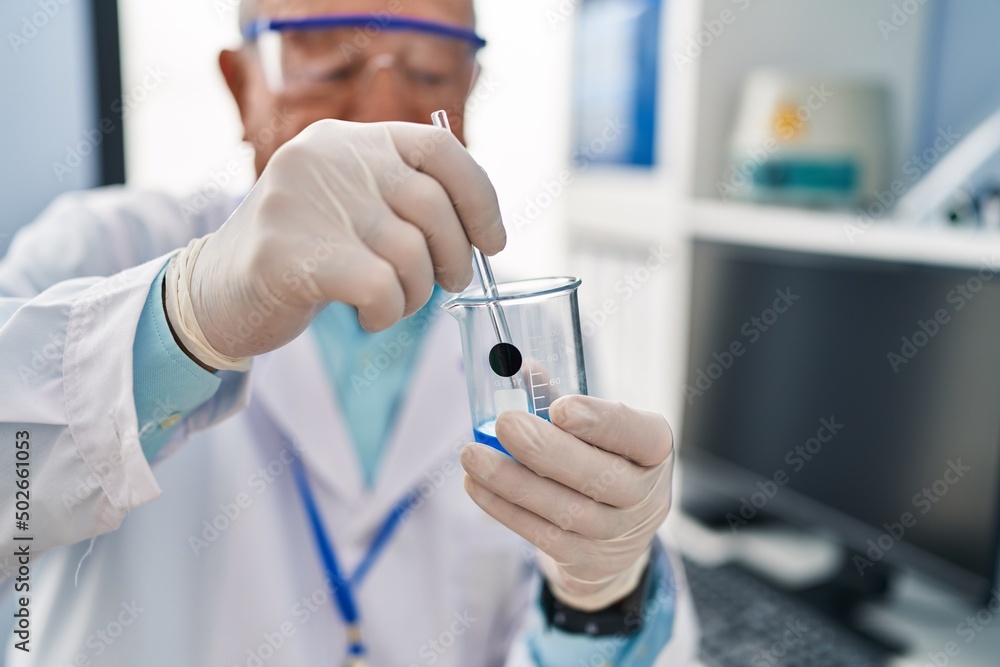 Senior man wearing scientist uniform mixing liquid at laboratory Senior man wearing scientist uniform mixing liquid at laboratory