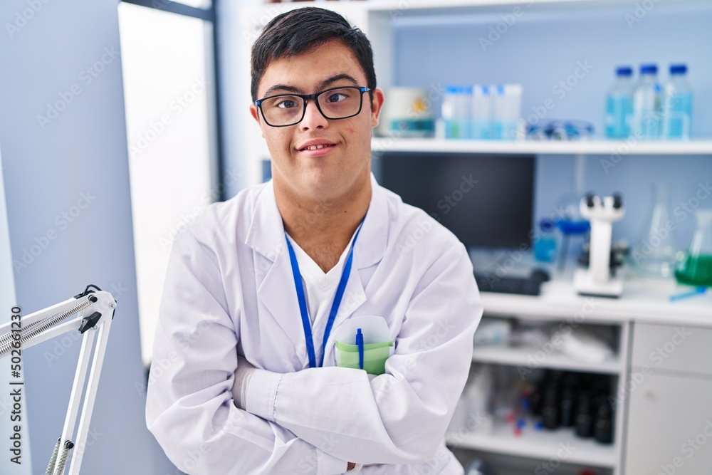 Down syndrome man wearing scientist uniform standing with arms crossed gesture at laboratory Down syndrome man wearing scientist uniform standing with arms crossed gesture at laboratory