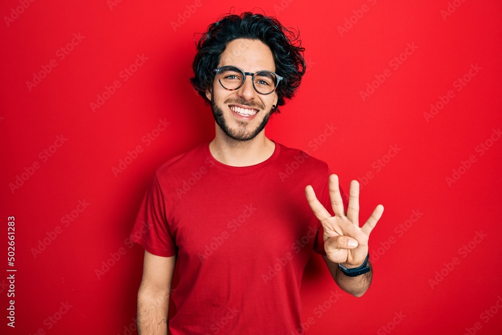 Handsome hispanic man wearing casual t shirt and glasses showing and pointing up with fingers number four while smiling confident and happy. Handsome hispanic man wearing casual t shirt and glasses showing and pointing up with fingers number four while smiling confident and happy.