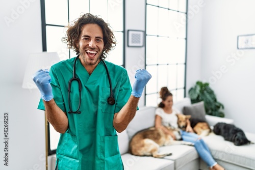 Fototapeta Naklejka Na Ścianę i Meble -  Young veterinarian man checking dogs at home screaming proud, celebrating victory and success very excited with raised arms
