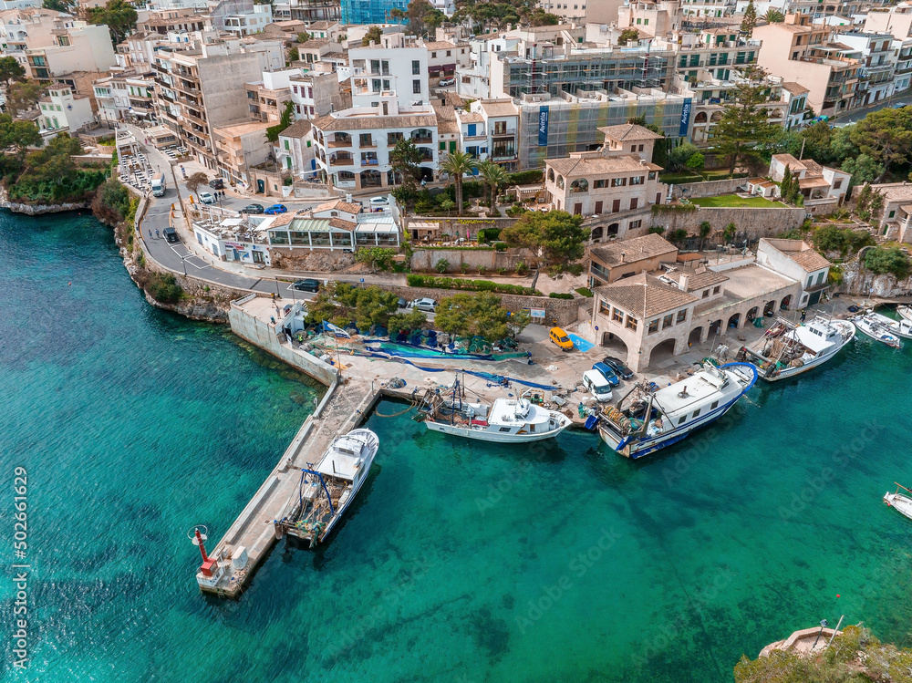 Aerial view of the fishing village in Mallorca, Spain. Boats docked by the pier.