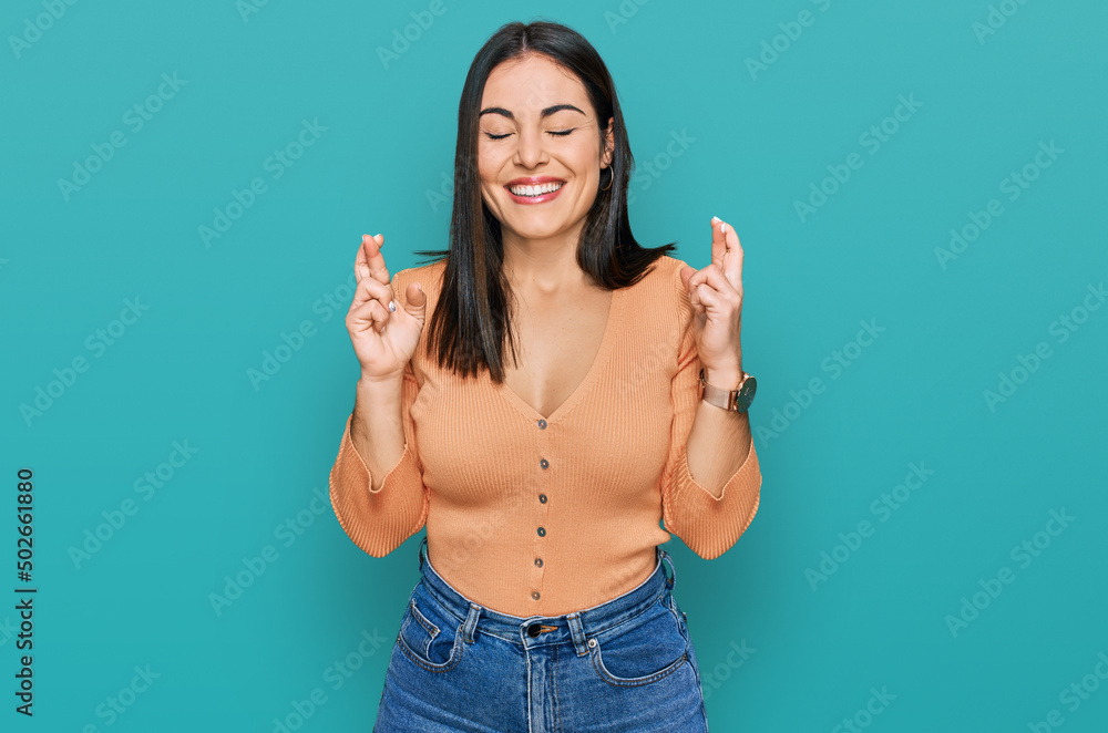 Young hispanic woman wearing casual clothes gesturing finger crossed smiling with hope and eyes closed. luck and superstitious concept. Young hispanic woman wearing casual clothes gesturing finger crossed smiling with hope and eyes closed. luck and superstitious concept.