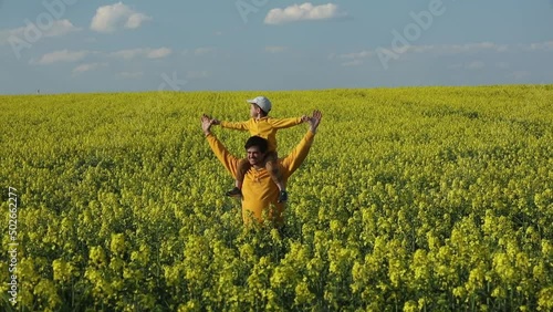 Father with a son in rapeseed field in spring time