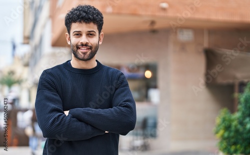 Fotografia Young arab man smiling confident standing with arms crossed gesture at street