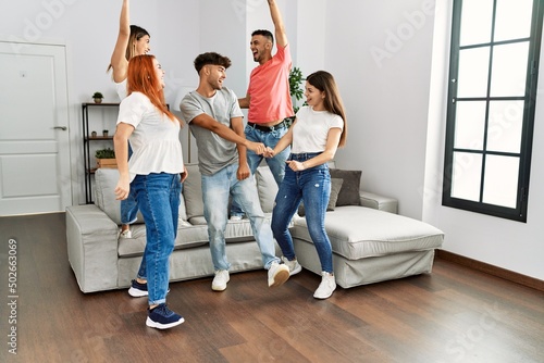 Group of young friends smiling happy and dancing at home.