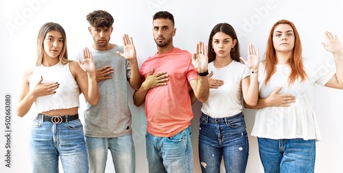 Quadro su tela Group of young friends standing together over isolated background swearing with