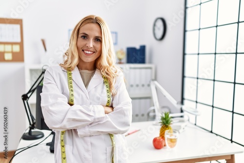 Beautiful blonde nutritionist woman at dietitian clinic happy face smiling with crossed arms looking at the camera. positive person.