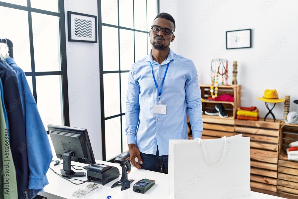 Young african man working as manager at retail boutique puffing cheeks with funny face. mouth inflated with air, crazy expression. Young african man working as manager at retail boutique puffing cheeks with funny face. mouth inflated with air, crazy expression.