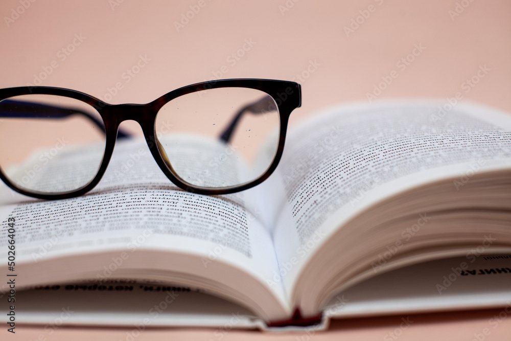 book with glasses on a beige background
