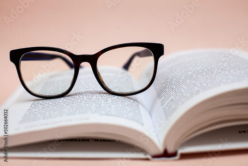 book with glasses on a beige background