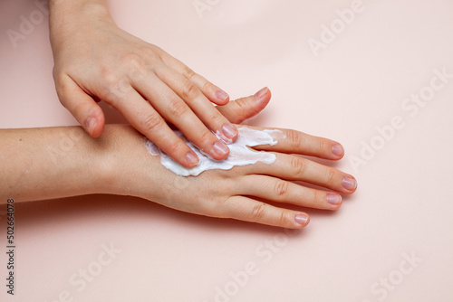 cream on hand on pink background