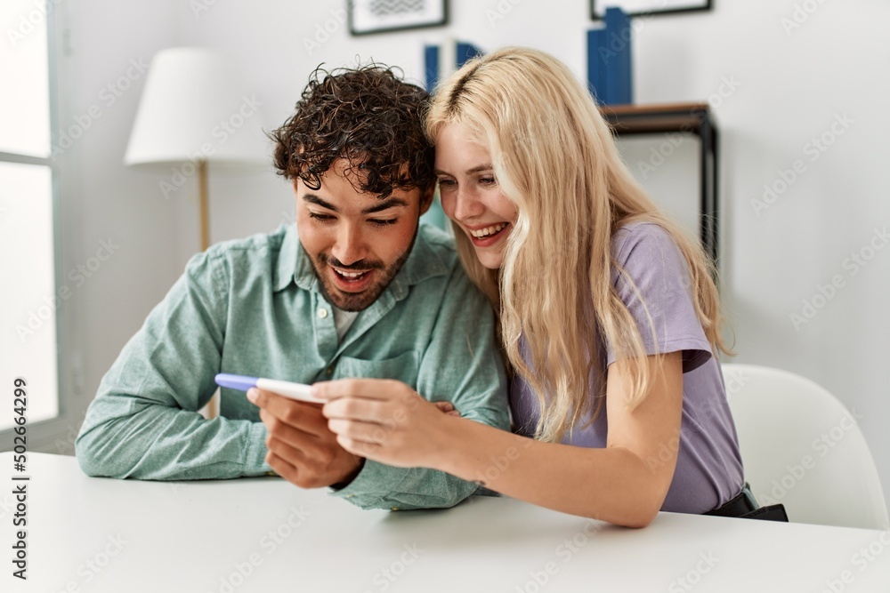 Young couple smiling happy looking pregnant test result at home. Young couple smiling happy looking pregnant test result at home.